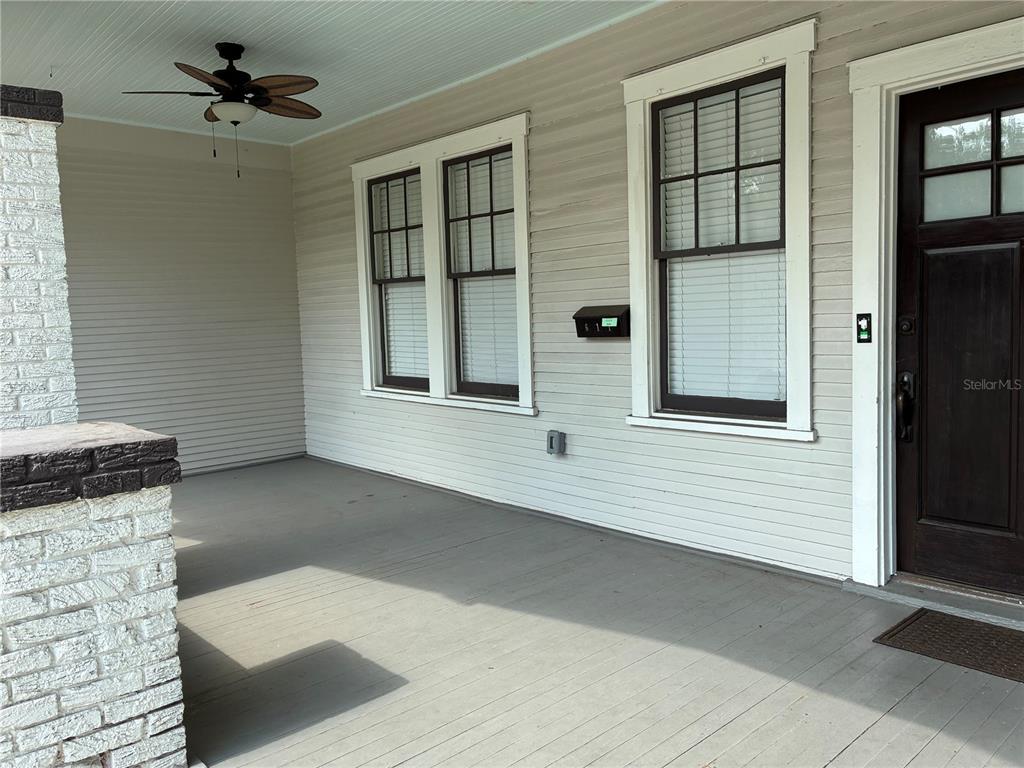 A covered front porch features a ceiling fan, light-colored siding, and a dark wooden door — 611 S WILLOW AVENUE, TAMPA, FL