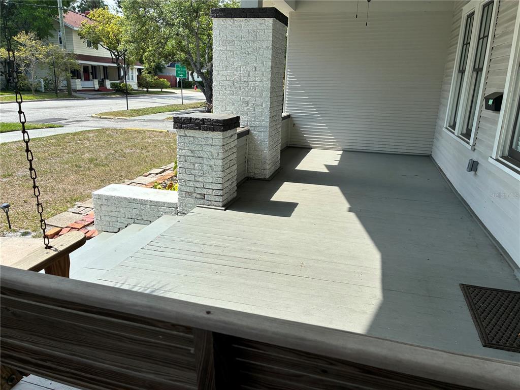 A covered front porch features a wooden swing, painted floorboards, and white brick pillars — 611 S WILLOW AVENUE, TAMPA, FL