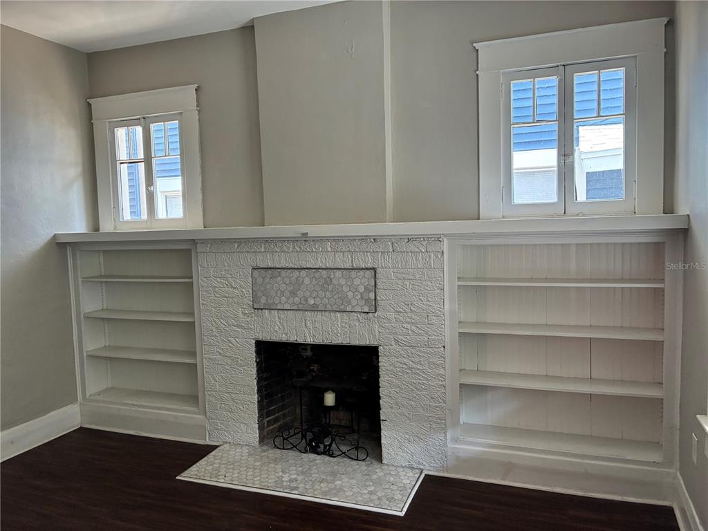 A living room features a white brick fireplace flanked by built-in shelves and two windows — 611 S WILLOW AVENUE, TAMPA, FL
