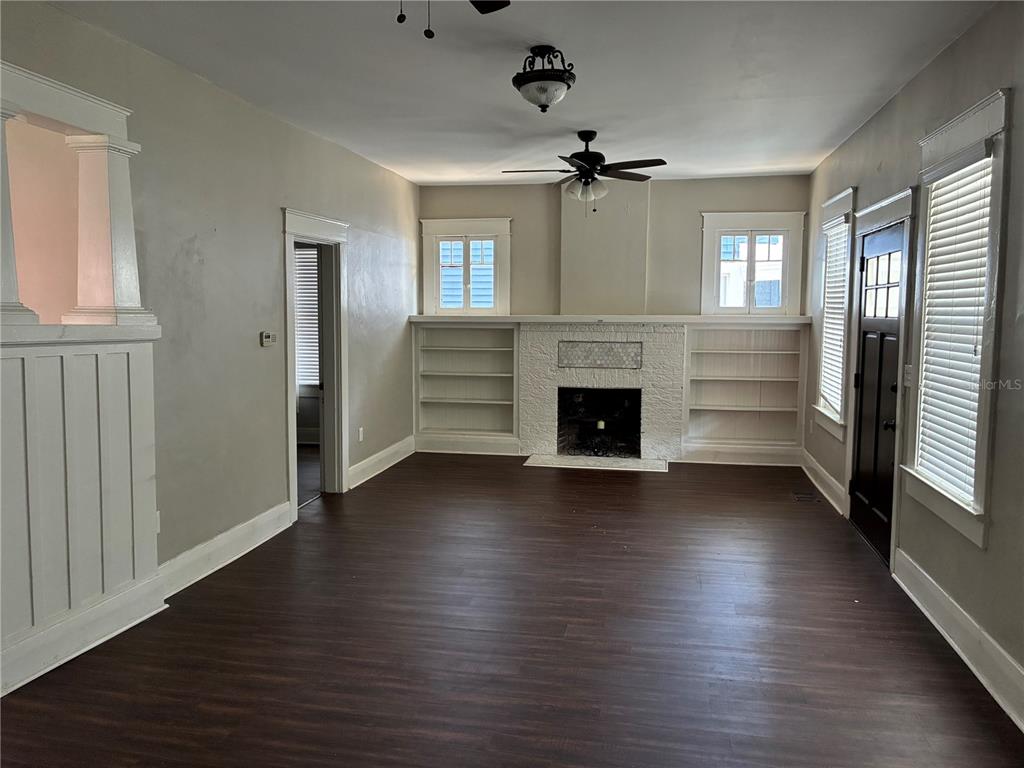 A living room features dark wood flooring, a white brick fireplace, and built-in bookshelves — 611 S WILLOW AVENUE, TAMPA, FL