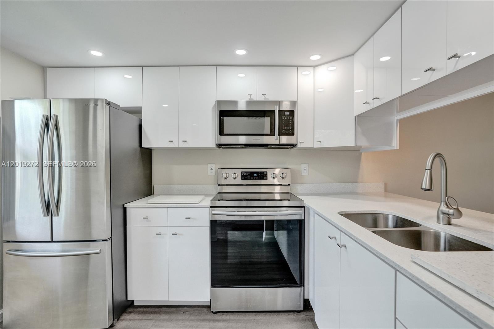 A modern kitchen features white cabinets, stainless steel appliances, and light-colored countertops — 1108 Bahama Bnd # B1, Coconut Creek FL 33066, COCONUT CREEK, FL