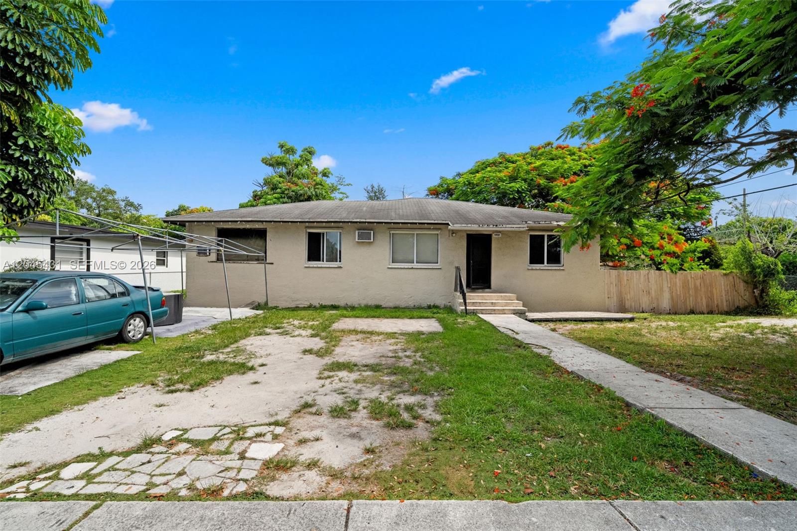 A single-story beige house with a front yard, driveway, and a parked teal car — 5901 SW 62nd St, Miami FL 33143, MIAMI, FL
