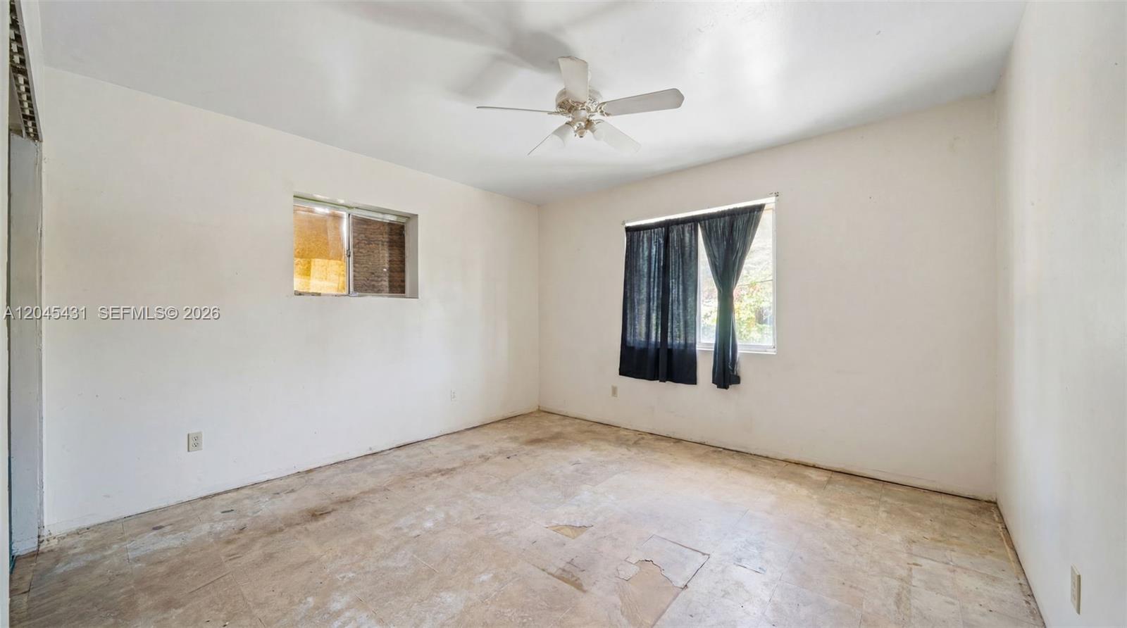An empty bedroom features white walls, a ceiling fan, and worn, light-colored floor tiles — 5901 SW 62nd St, Miami FL 33143, MIAMI, FL