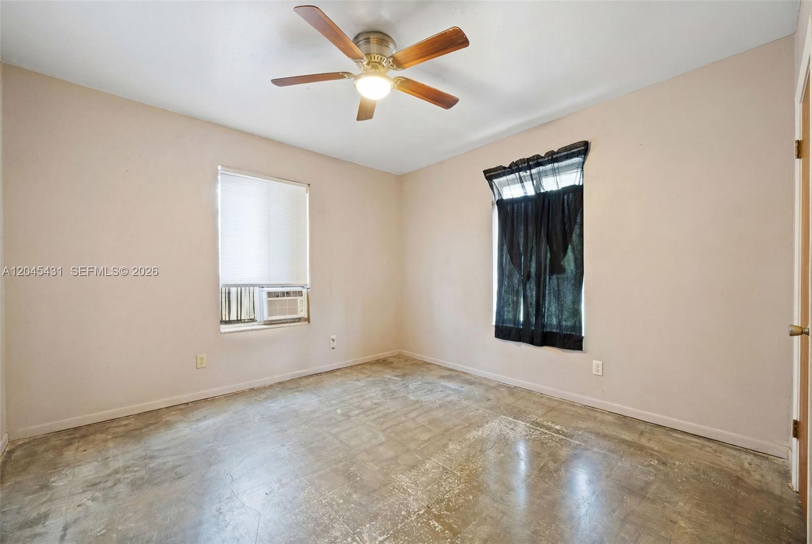 An empty bedroom features a ceiling fan, two windows, and unfinished concrete flooring — 5901 SW 62nd St, Miami FL 33143, MIAMI, FL