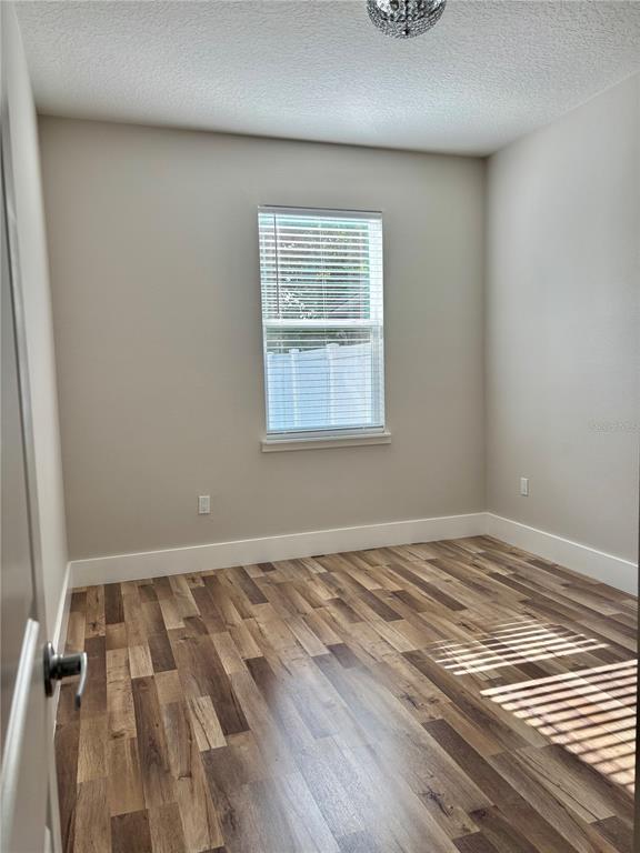 An empty room with light-colored walls, wood-look flooring, and a single window with blinds — 1001 LA MIRADA COURT, KISSIMMEE, FL