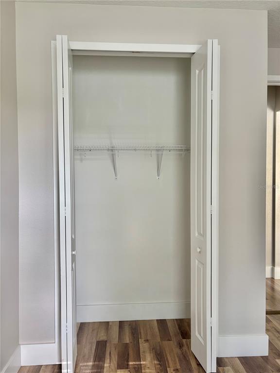 An open closet with a wire shelf and white bi-fold doors in a room — 1001 LA MIRADA COURT, KISSIMMEE, FL