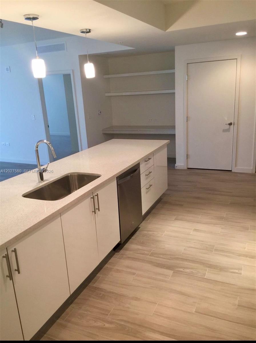 A modern kitchen features white cabinets, a quartz island with a sink, and light flooring — 999 SW 1st Ave # 2005, Miami FL 33130, MIAMI, FL
