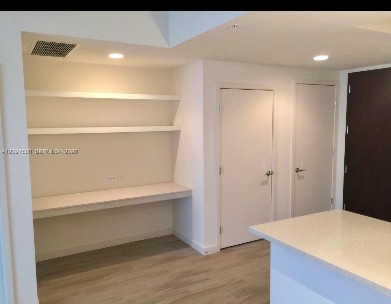 A room features a built-in desk with two shelves, light wood flooring, and two doors — 999 SW 1st Ave # 2005, Miami FL 33130, MIAMI, FL