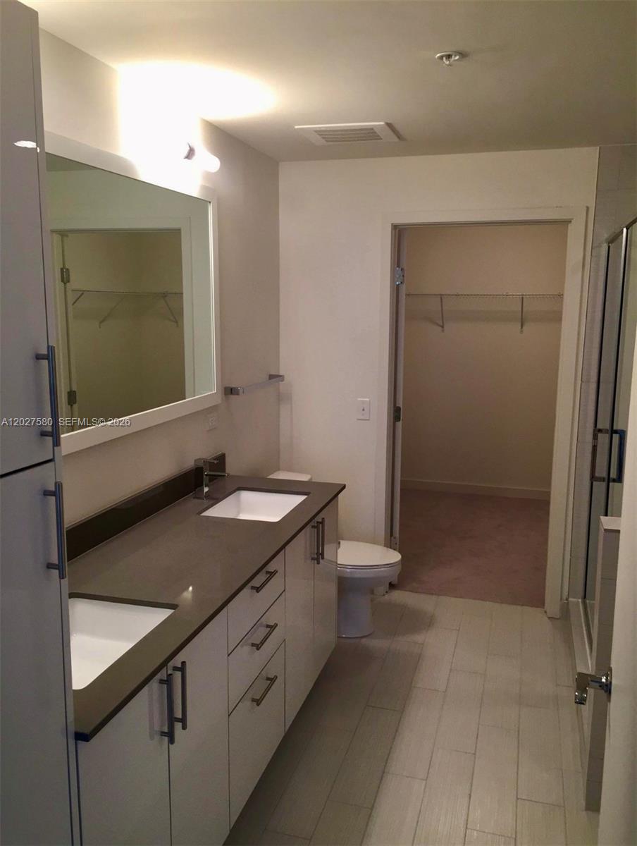 A modern bathroom features a double vanity with a dark countertop and a walk-in closet — 999 SW 1st Ave # 2005, Miami FL 33130, MIAMI, FL