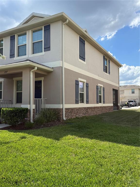 A two-story house exterior features tan stucco, dark shutters, and a stone veneer base — 1847 RED CANYON DRIVE, KISSIMMEE, FL