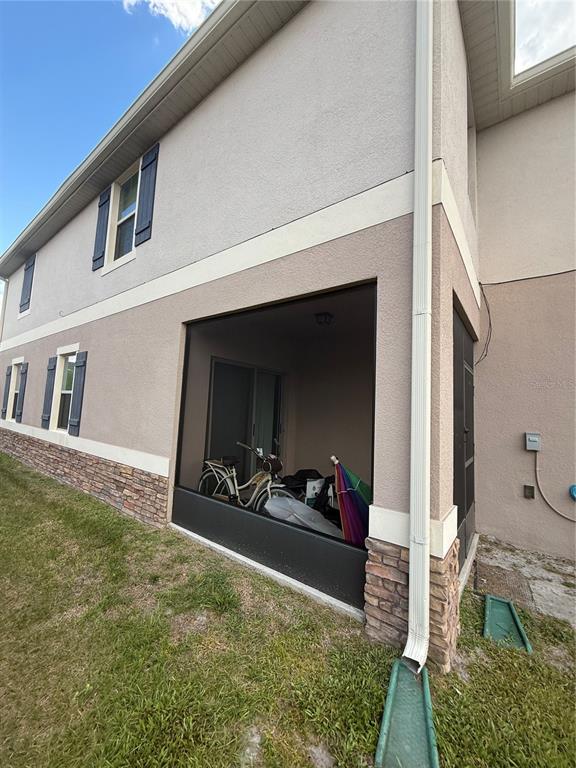 The exterior of a two-story home features a screened-in patio, stone veneer, and blue shutters — 1847 RED CANYON DRIVE, KISSIMMEE, FL