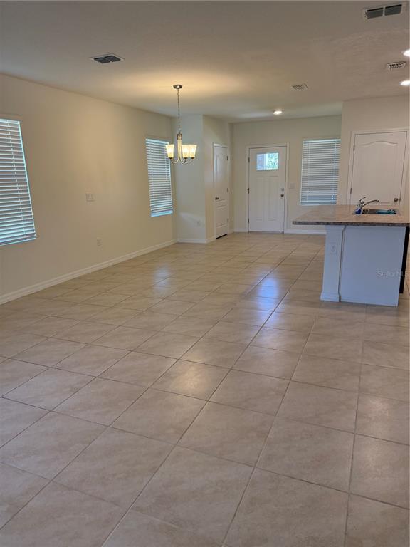An open-concept room features light-colored tile flooring, a kitchen island, and a front entryway — 1847 RED CANYON DRIVE, KISSIMMEE, FL