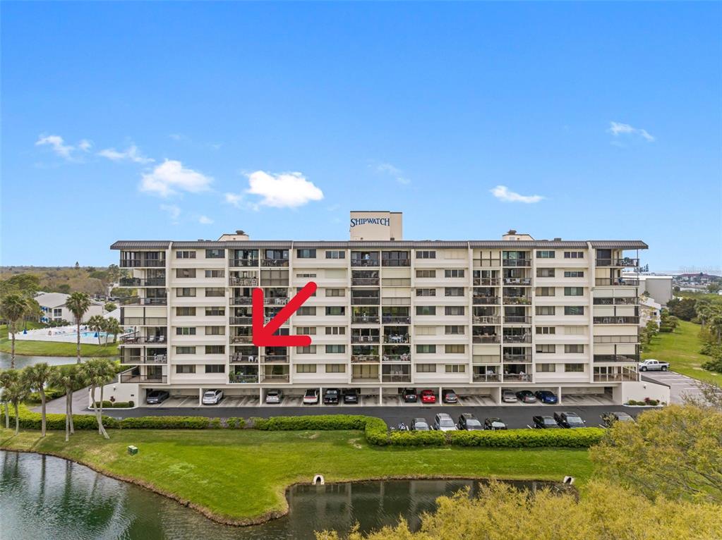 An exterior view of the Shipwatch condominium building with a red arrow pointing to a balcony — 11590 SHIPWATCH DRIVE UNIT 347, LARGO, FL