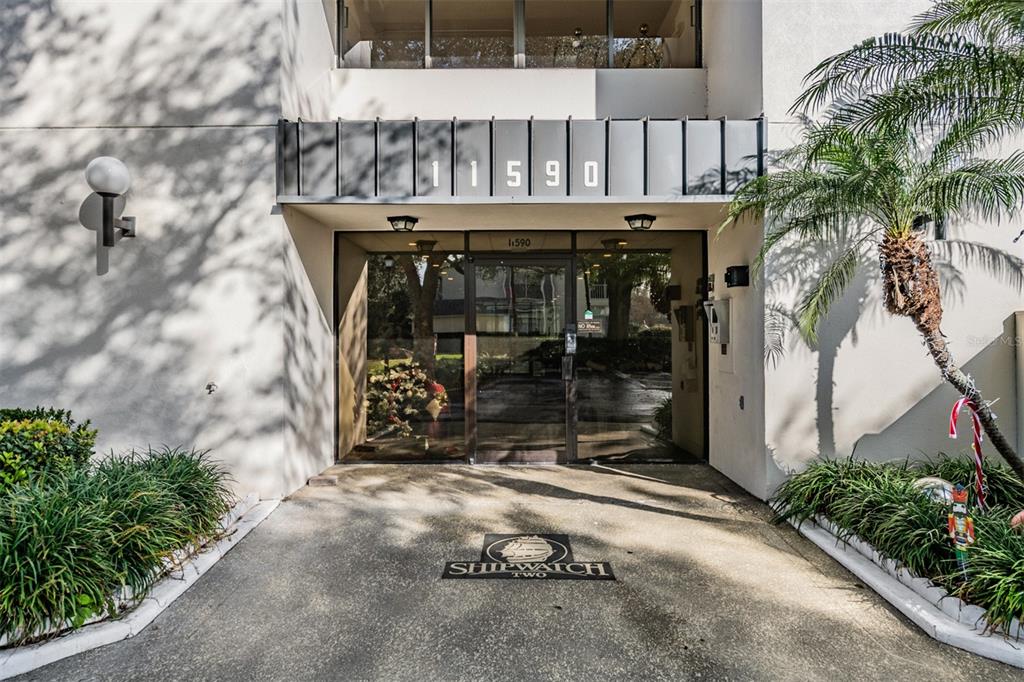 The exterior entrance of a building features a glass door and the number 11590 — 11590 SHIPWATCH DRIVE UNIT 347, LARGO, FL