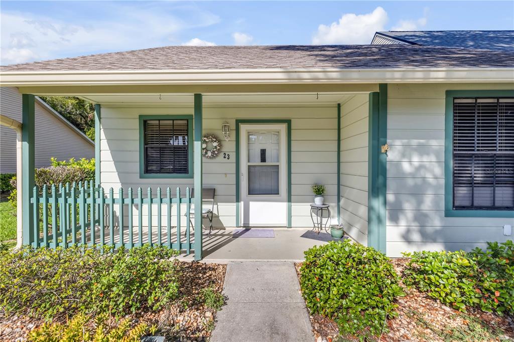 The exterior of a house features a covered porch, a white front door, and siding — 232 N RIDGEWOOD AVENUE UNIT 23, EDGEWATER, FL