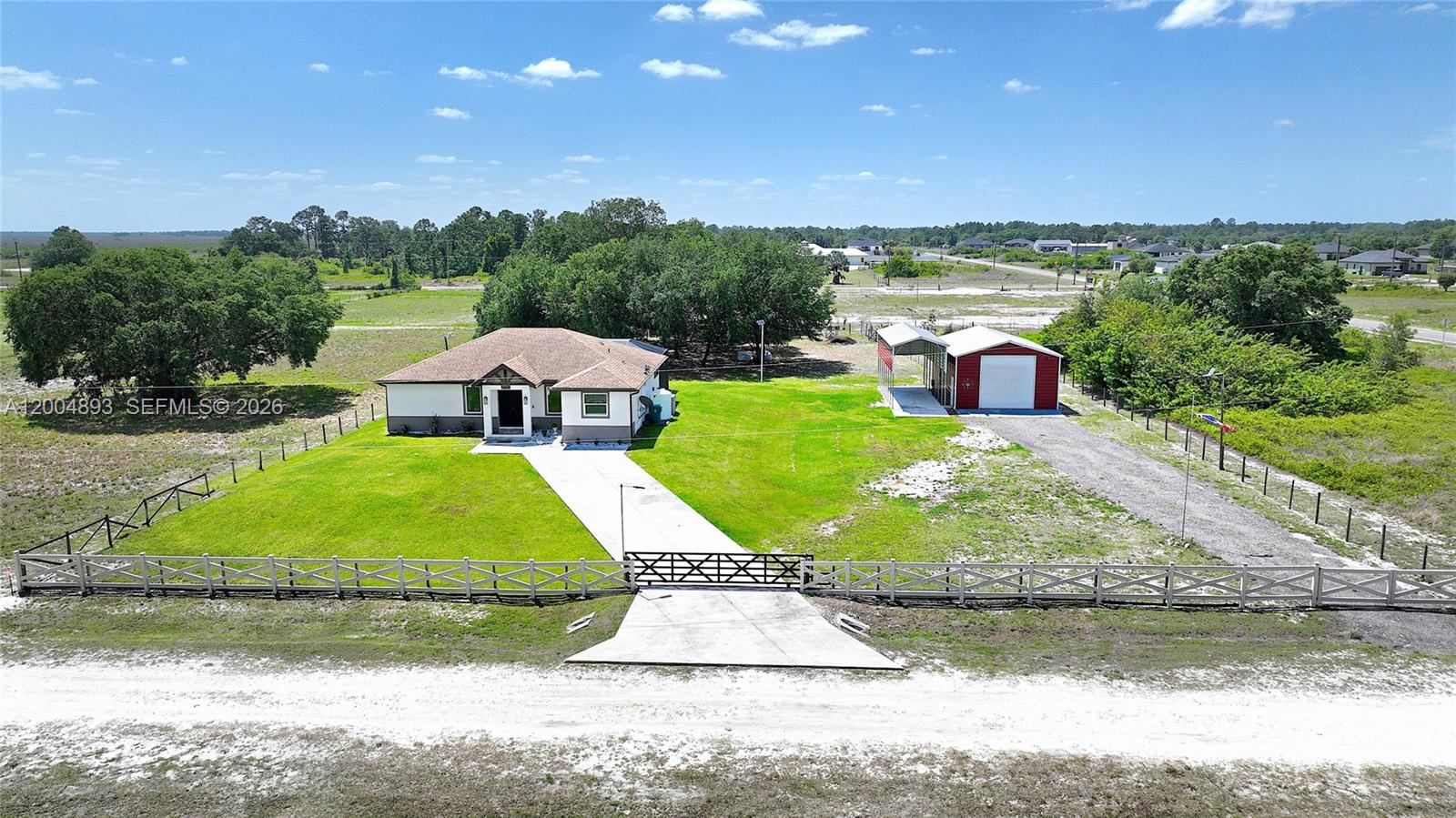An aerial view shows a single-story house with a detached garage on a grassy lot — 7655 17th Place, La Belle FL 33935, LA BELLE, FL