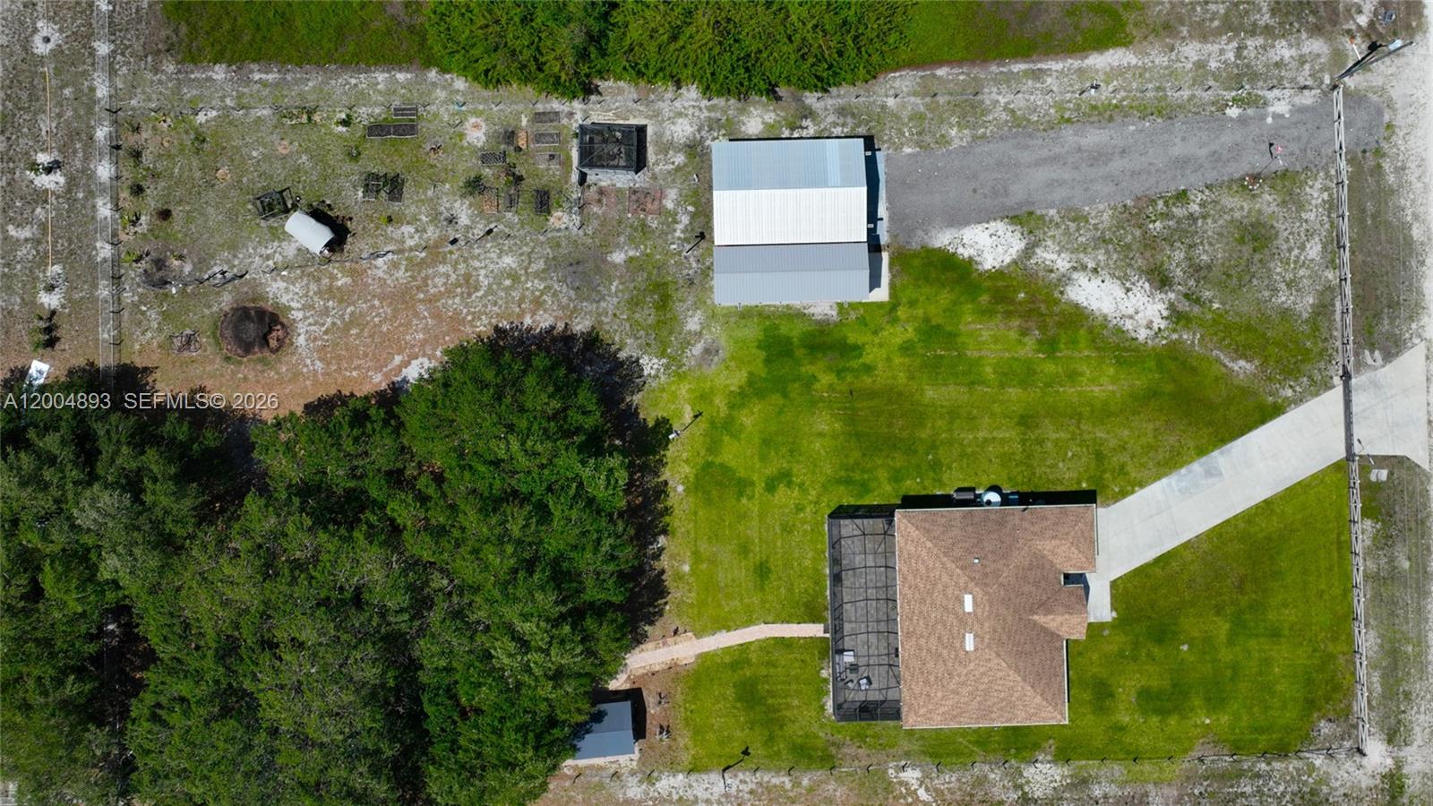 An aerial view shows a house with a pool cage, a detached garage, and trees — 7655 17th Place, La Belle FL 33935, LA BELLE, FL