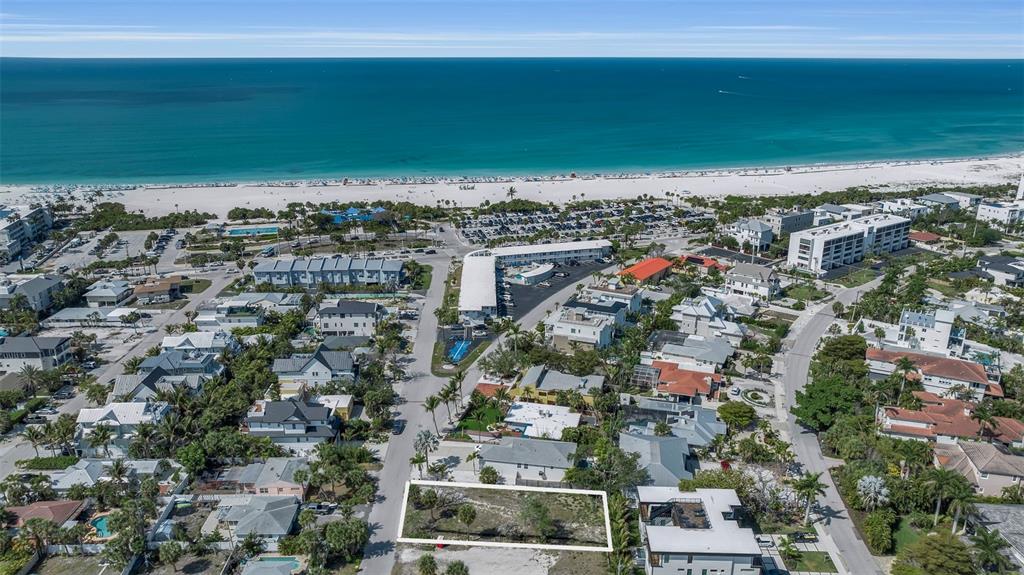An aerial view shows a vacant rectangular lot surrounded by residential buildings near a beach — 243 COOLIDGE DRIVE, SARASOTA, FL