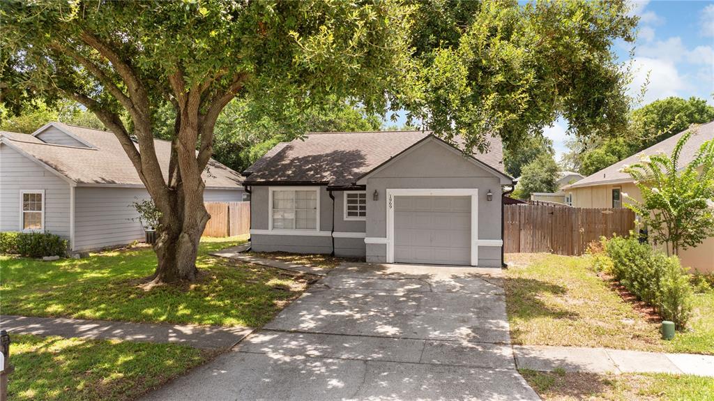 A gray single-story house with a front-facing garage and a large tree in the yard — 1969 SHEELER OAKS DRIVE, APOPKA, FL