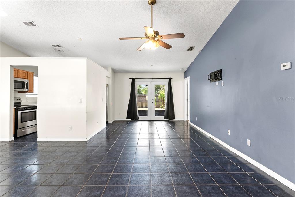 A living area with dark tile flooring, a blue accent wall, and glass patio doors — 1969 SHEELER OAKS DRIVE, APOPKA, FL