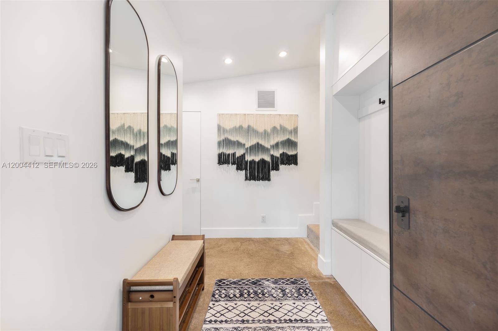 A modern entryway features a wooden bench, two oval mirrors, and a wall-mounted tapestry — 3775 S Le Jeune Rd, Miami FL 33146, MIAMI, FL