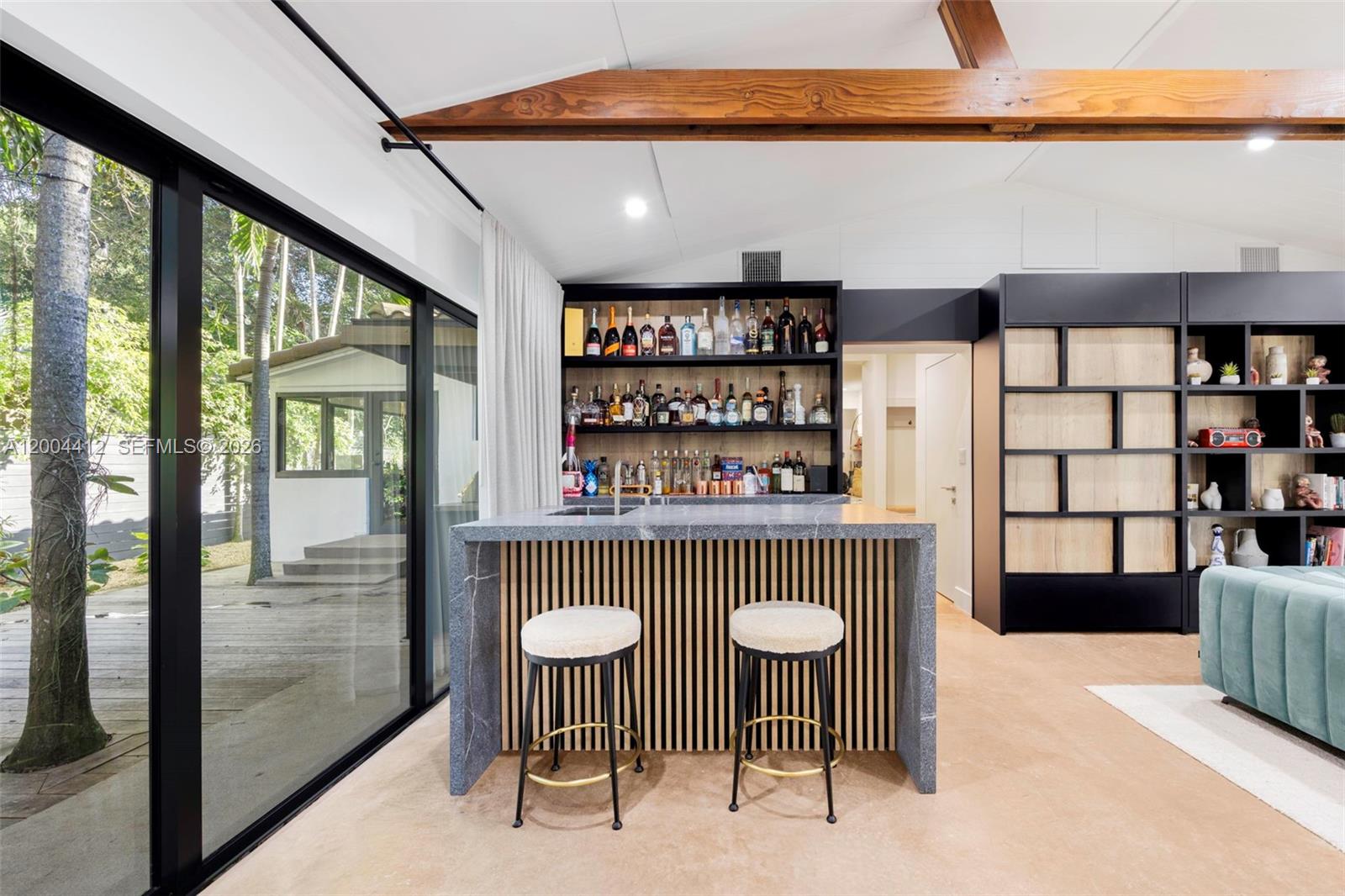 A modern home bar features a stone-topped island with wood slats and floor-to-ceiling windows — 3775 S Le Jeune Rd, Miami FL 33146, MIAMI, FL