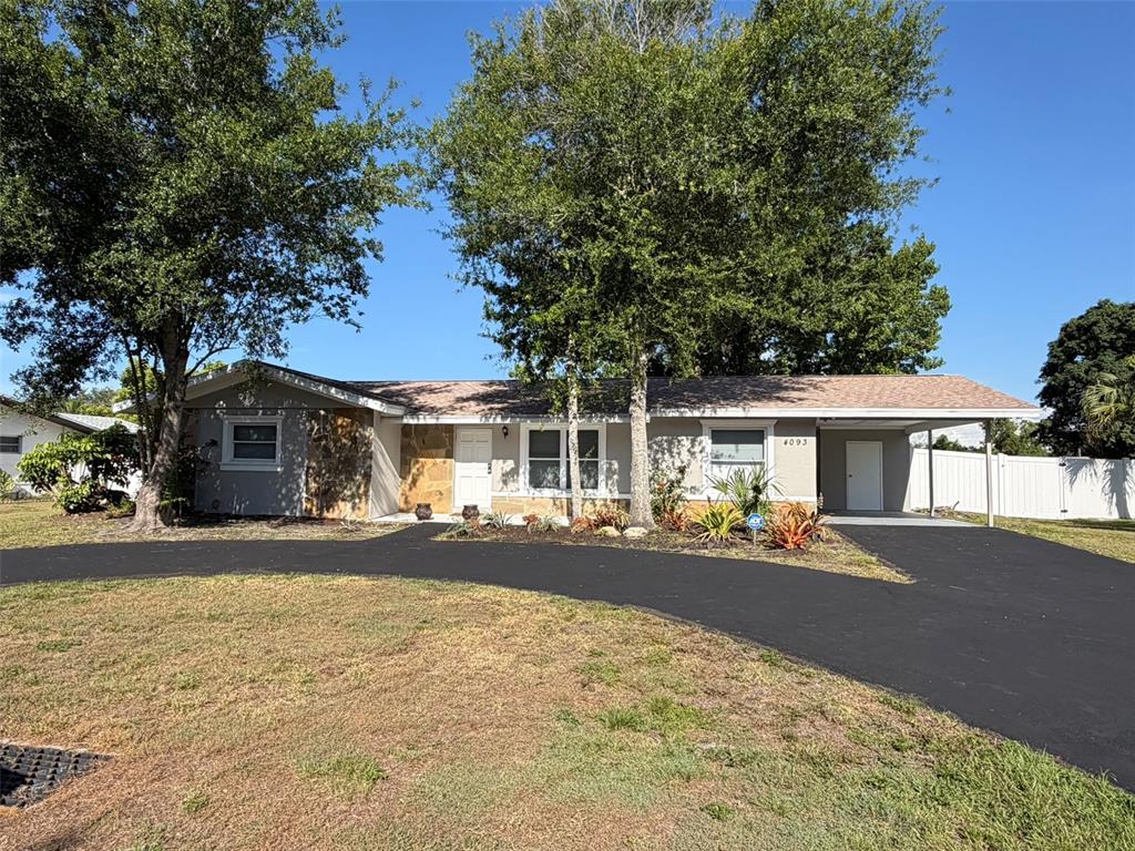 A single-story house with a gray exterior, a carport, and a curved asphalt driveway — 4093 DRANCE STREET, PUNTA GORDA, FL