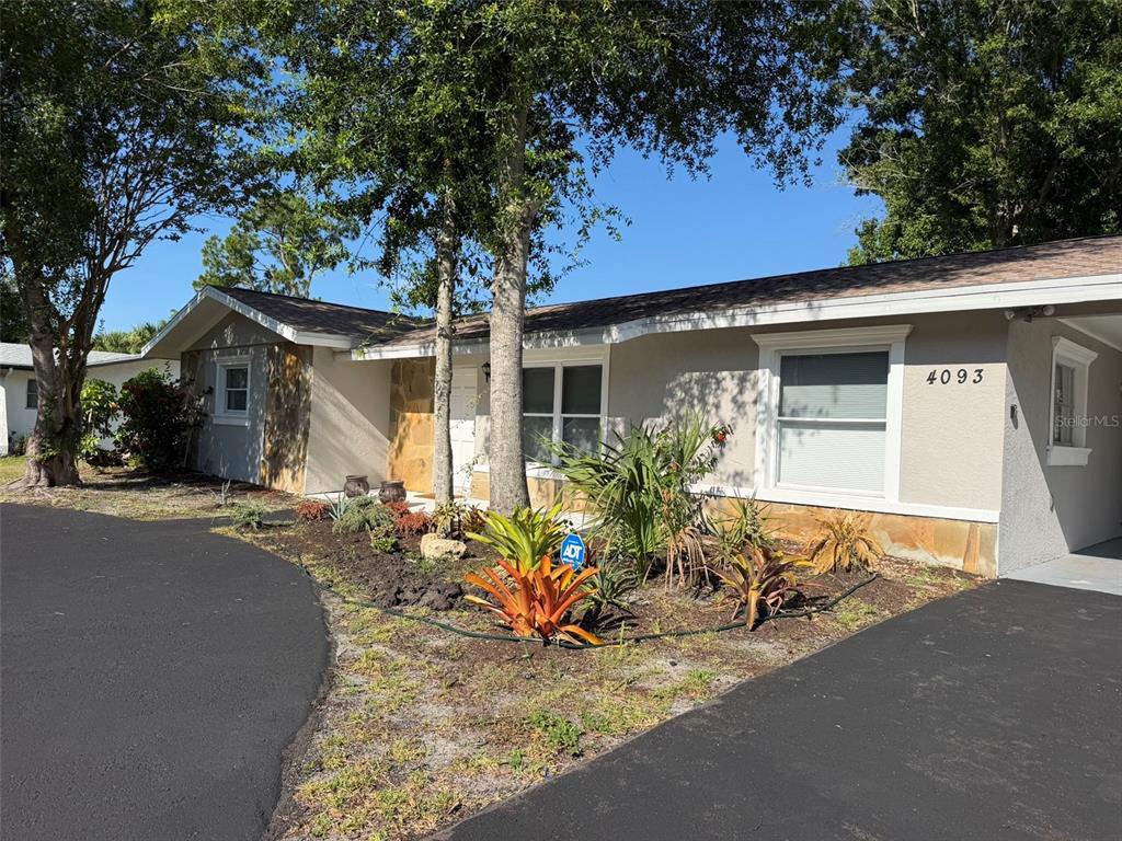 A single-story house with a beige exterior, stone accents, and a dark asphalt driveway — 4093 DRANCE STREET, PUNTA GORDA, FL