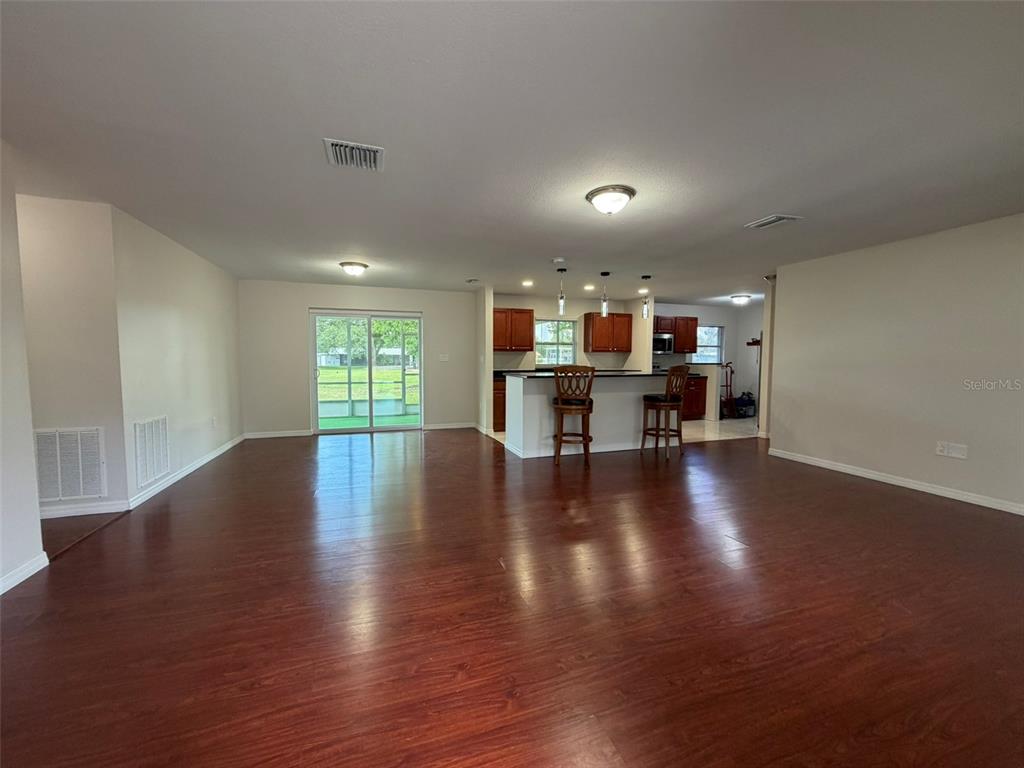 An open-concept living area features dark wood flooring, a kitchen island, and sliding glass doors — 4093 DRANCE STREET, PUNTA GORDA, FL