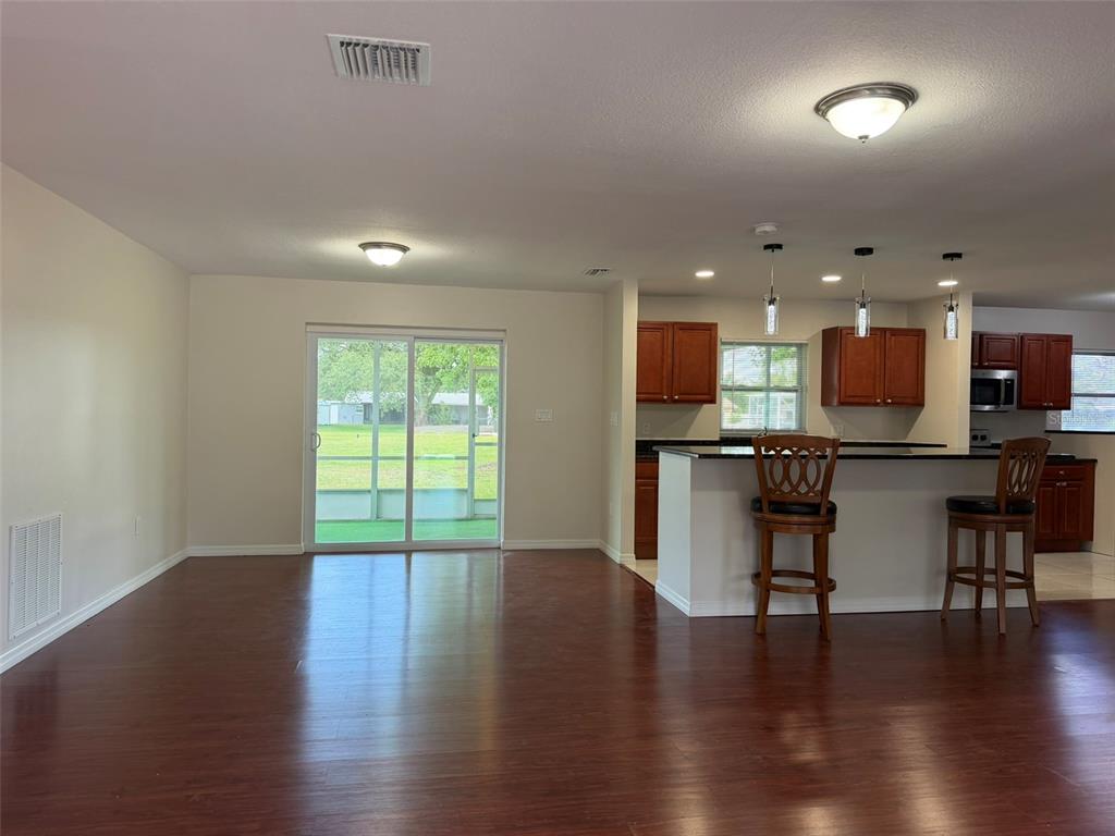 An open-concept kitchen and living area features dark wood flooring and a sliding glass door — 4093 DRANCE STREET, PUNTA GORDA, FL