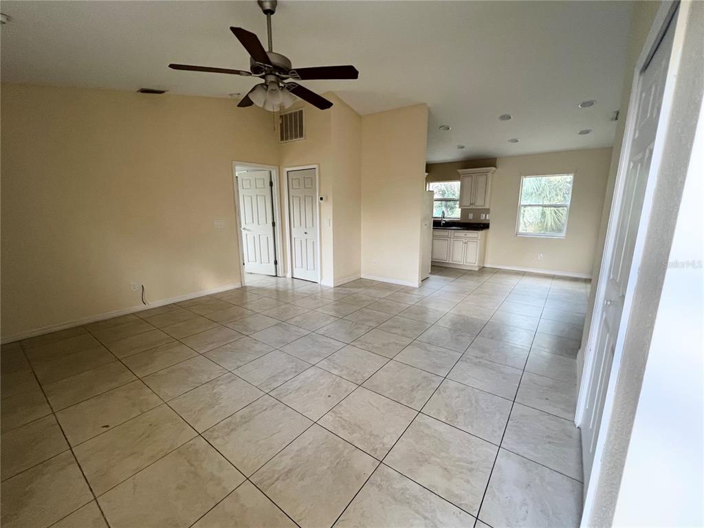 An open-concept living area with tile flooring, a ceiling fan, and an adjacent kitchen — 3281 EASY STREET, PORT CHARLOTTE, FL