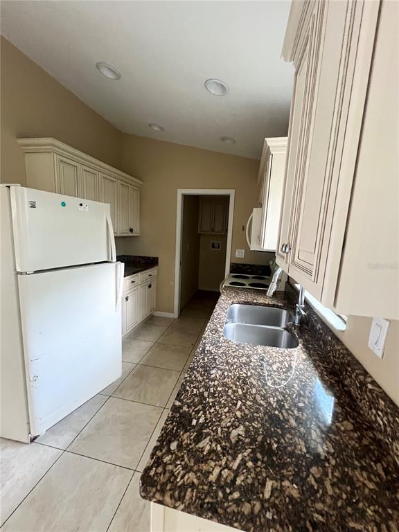 A kitchen features white cabinets, dark granite countertops, a white refrigerator, and tile flooring — 3281 EASY STREET, PORT CHARLOTTE, FL