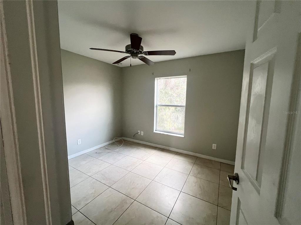 A bedroom with light gray walls, tile flooring, a ceiling fan, and a single window — 3281 EASY STREET, PORT CHARLOTTE, FL