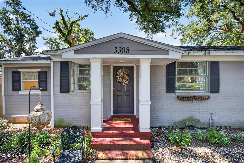 The exterior of a gray brick house features a covered entryway with white columns — 3308 SHERIDAN ROAD, JACKSONVILLE, FL
