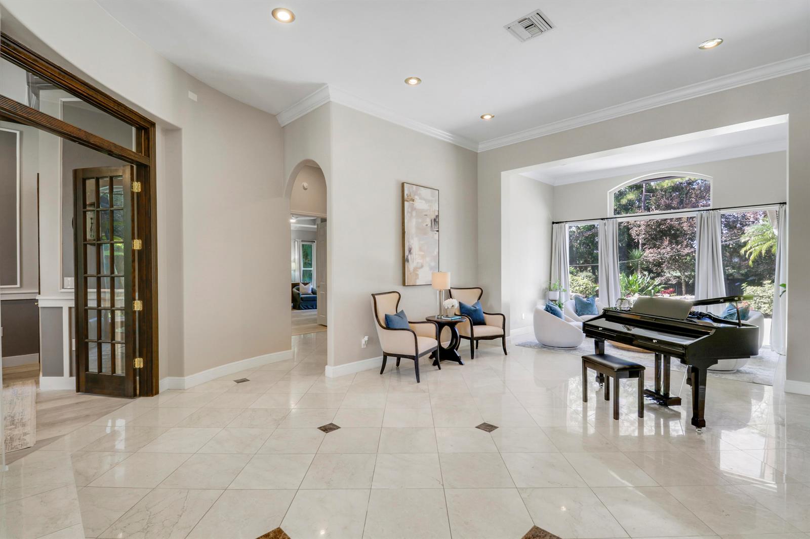 A spacious foyer with light tile floors features a grand piano and two accent chairs — 18512 SE Old Trail Drive E, Jupiter FL 33478, JUPITER, FL