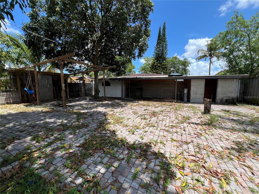 A backyard features a paved patio, a wooden pergola with a swing, and a house exterior — 845 NW 130TH STREET, NORTH MIAMI, FL