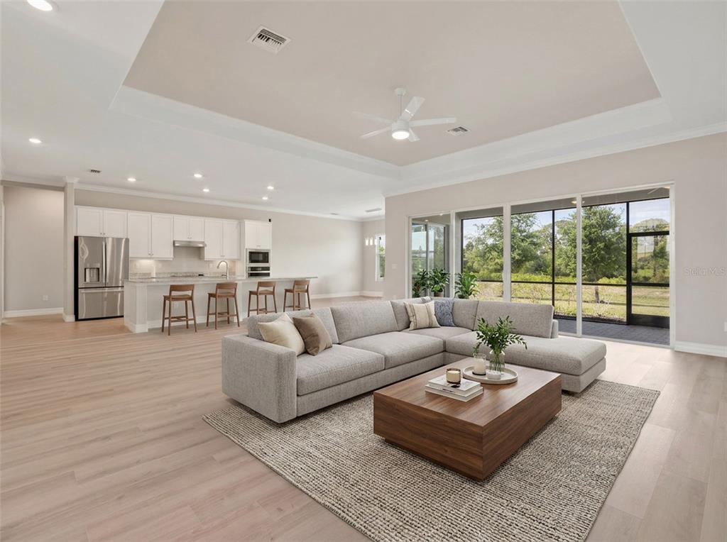 A modern open-concept living room and kitchen featuring light wood floors and a sectional sofa — 14500 PONCE DE LEON TRAIL, PORT CHARLOTTE, FL