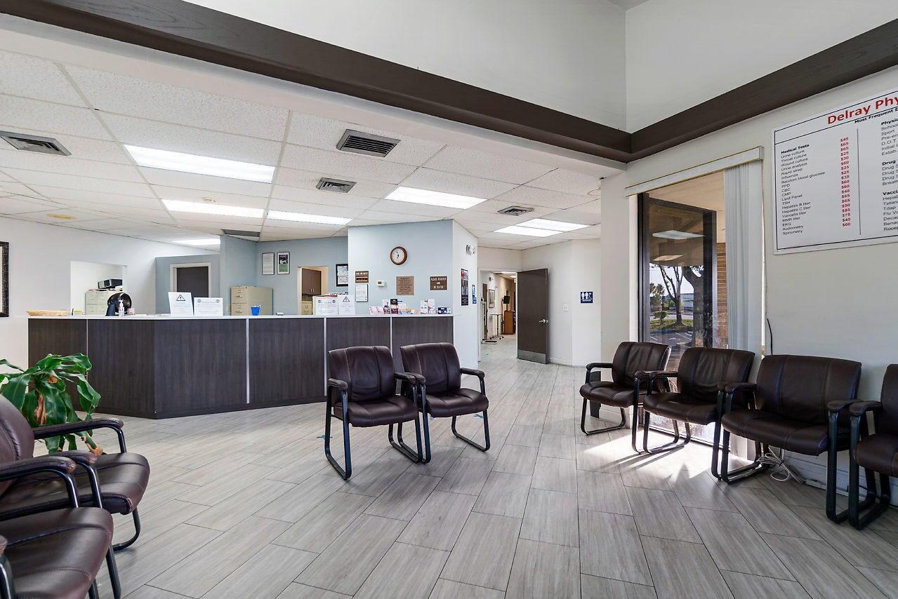 A medical office waiting room features a dark wood reception desk and brown leather chairs — 2280 W Atlantic Avenue, Delray Beach FL 33445, DELRAY BEACH, FL