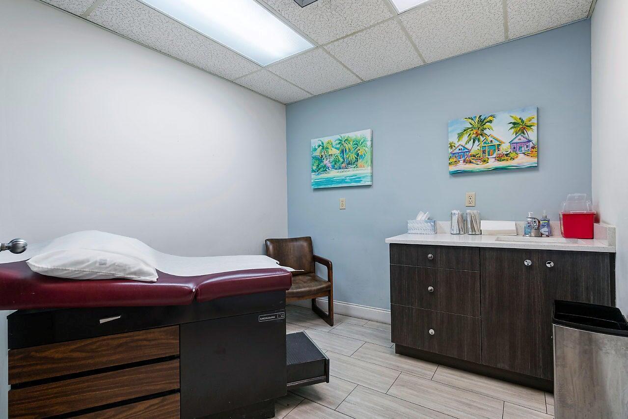 A medical examination room features a burgundy exam table, a brown chair, and dark cabinetry — 2280 W Atlantic Avenue, Delray Beach FL 33445, DELRAY BEACH, FL