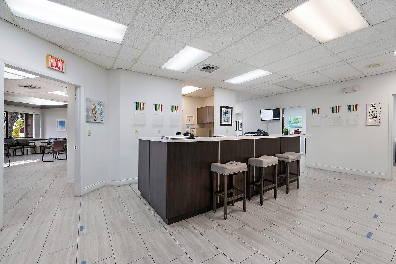 A reception area features a dark wood counter with three stools and light-colored tile flooring — 2280 W Atlantic Avenue, Delray Beach FL 33445, DELRAY BEACH, FL