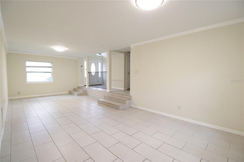 A bright, tiled living room features a split-level floor plan with steps and a railing — 10907 SW 24TH AVENUE, GAINESVILLE, FL