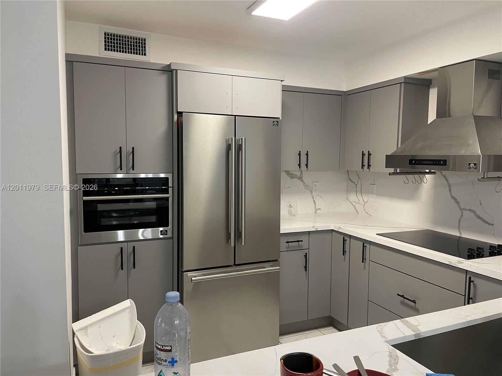 A modern kitchen features gray cabinets, stainless steel appliances, and white marble-patterned countertops — 1621 Collins Ave # 707, Miami Beach FL 33139, MIAMI BEACH, FL