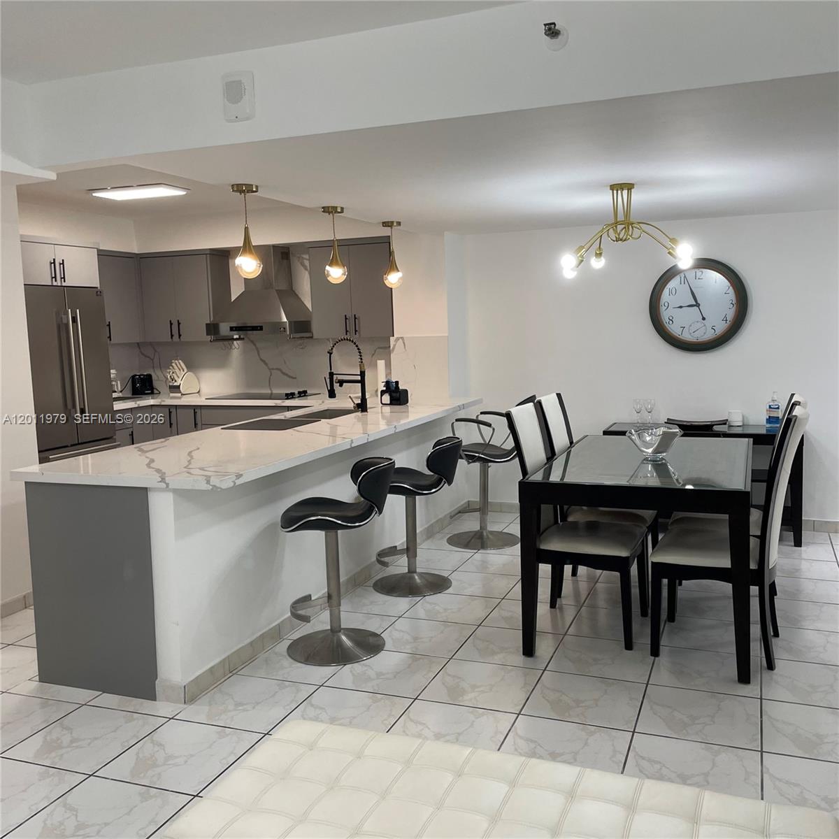 A modern kitchen with gray cabinets and a white marble-patterned island with bar stools — 1621 Collins Ave # 707, Miami Beach FL 33139, MIAMI BEACH, FL