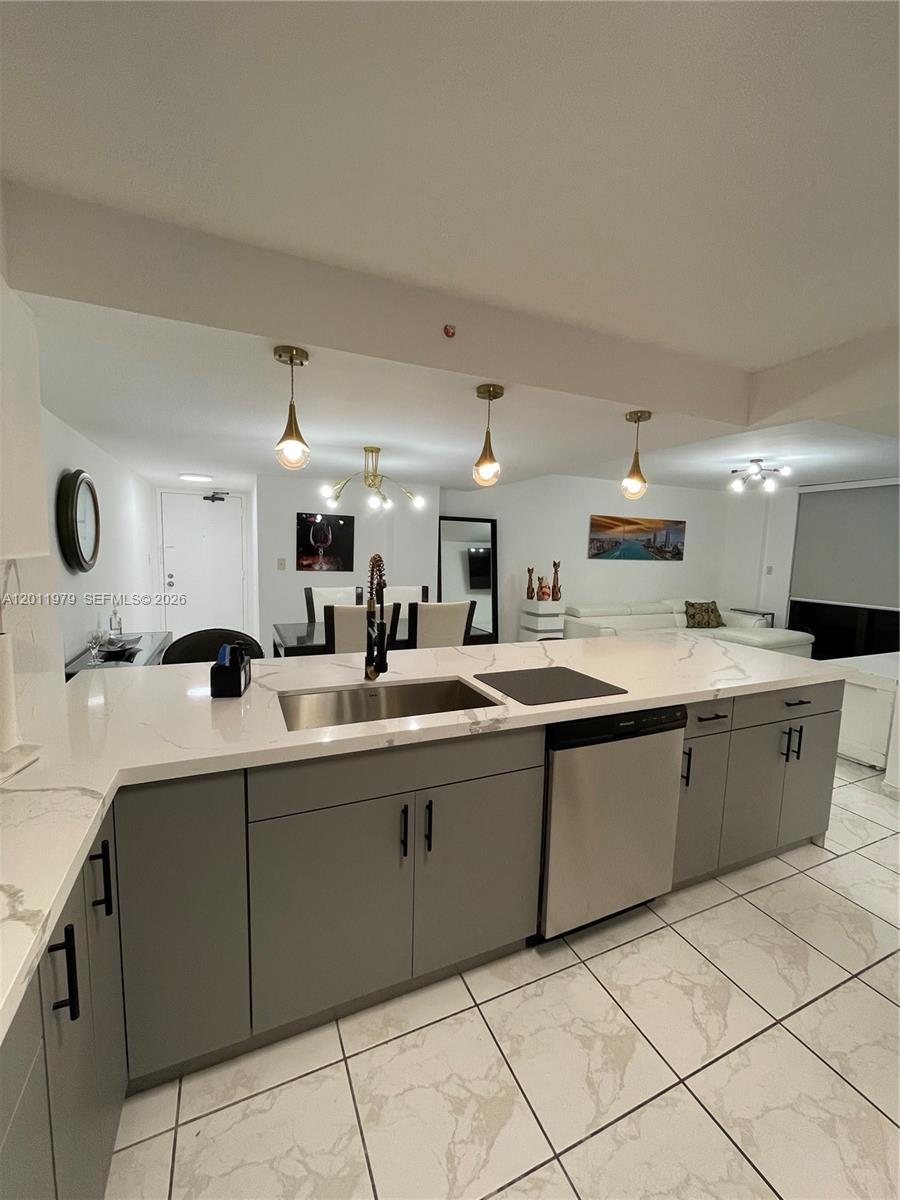 A kitchen with gray cabinets, white marble-patterned countertops, and a stainless steel sink — 1621 Collins Ave # 707, Miami Beach FL 33139, MIAMI BEACH, FL