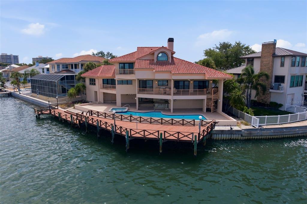 A waterfront house with a tiled roof, a swimming pool, and a large wooden deck — 2869 SEABREEZE DRIVE S, GULFPORT, FL