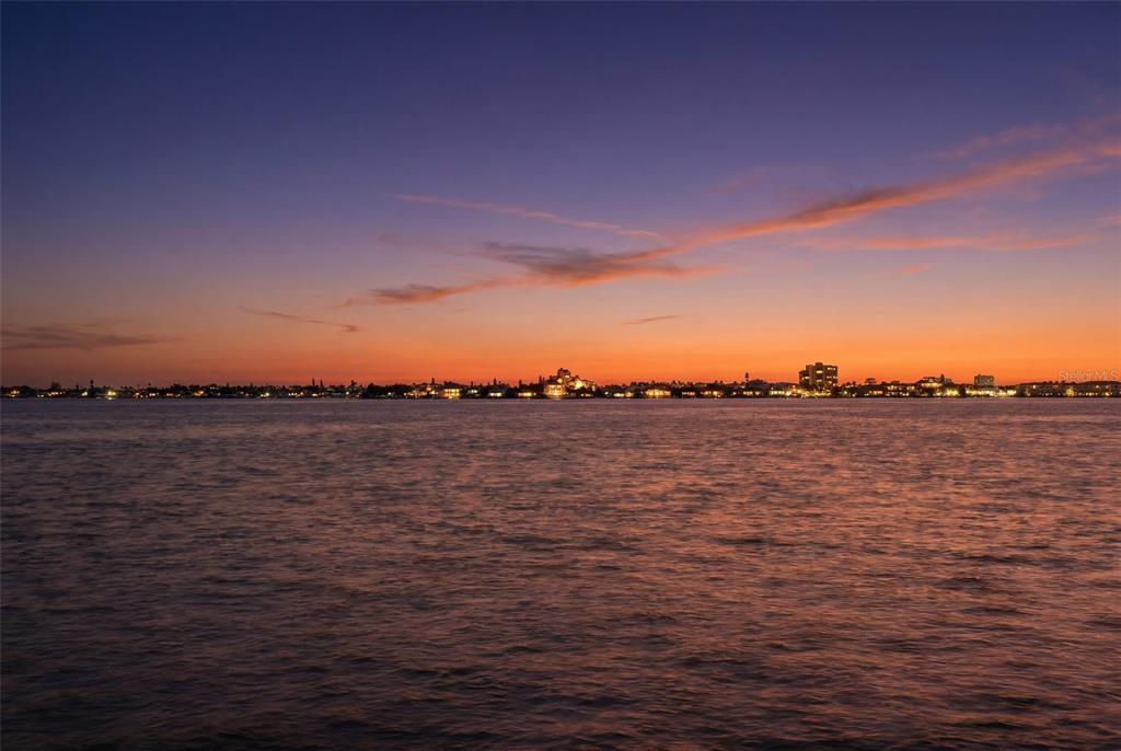 A wide-angle view of a calm body of water at sunset with a distant city skyline — 2869 SEABREEZE DRIVE S, GULFPORT, FL