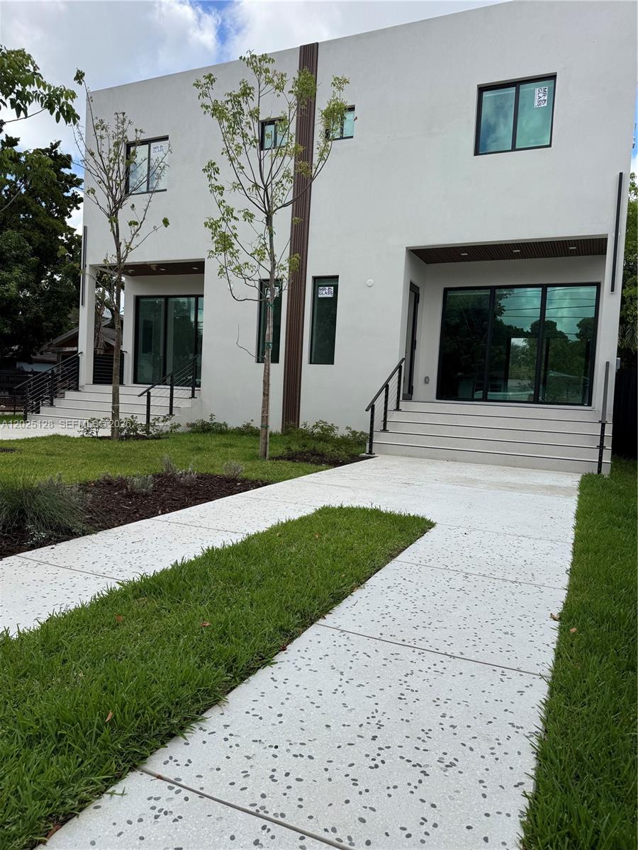 A modern two-story duplex with white stucco walls, large glass windows, and concrete walkways — 1924 NW 27th St, Miami FL 33142, MIAMI, FL