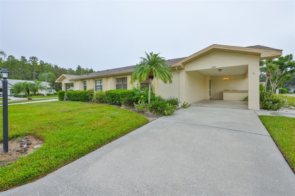 A single-story house with a beige exterior, a concrete driveway, and an attached carport — 2122 HEREFORD DRIVE UNIT 511, SUN CITY CENTER, FL
