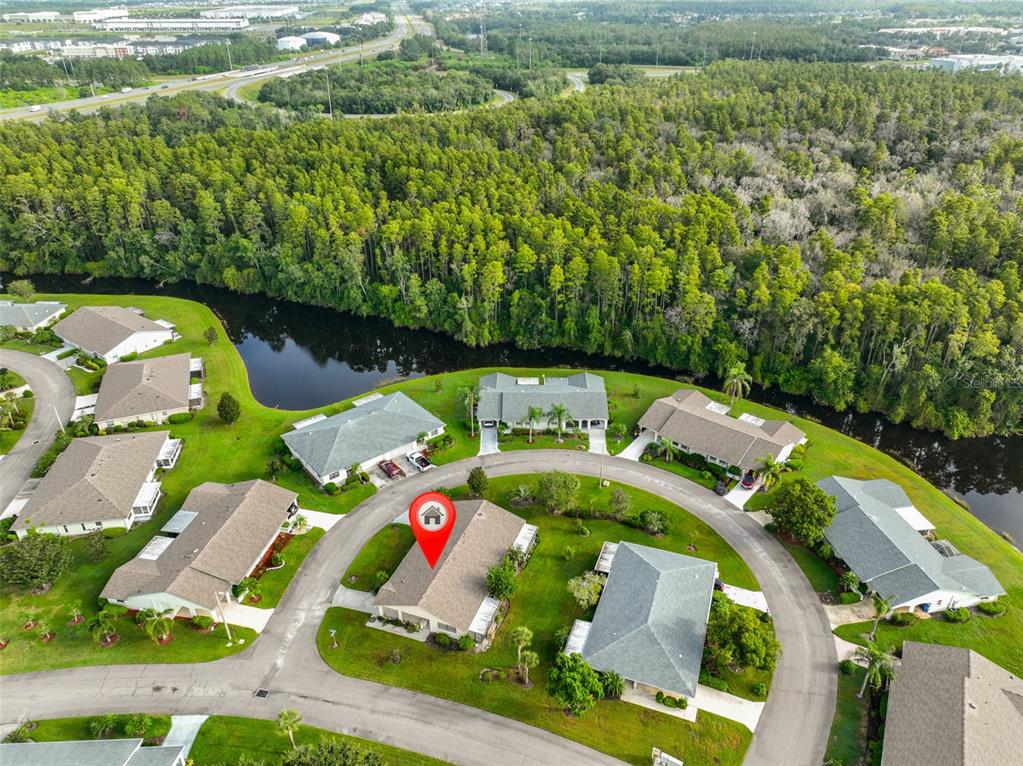 An aerial view shows a suburban neighborhood with houses surrounding a pond and dense woods — 2122 HEREFORD DRIVE UNIT 511, SUN CITY CENTER, FL