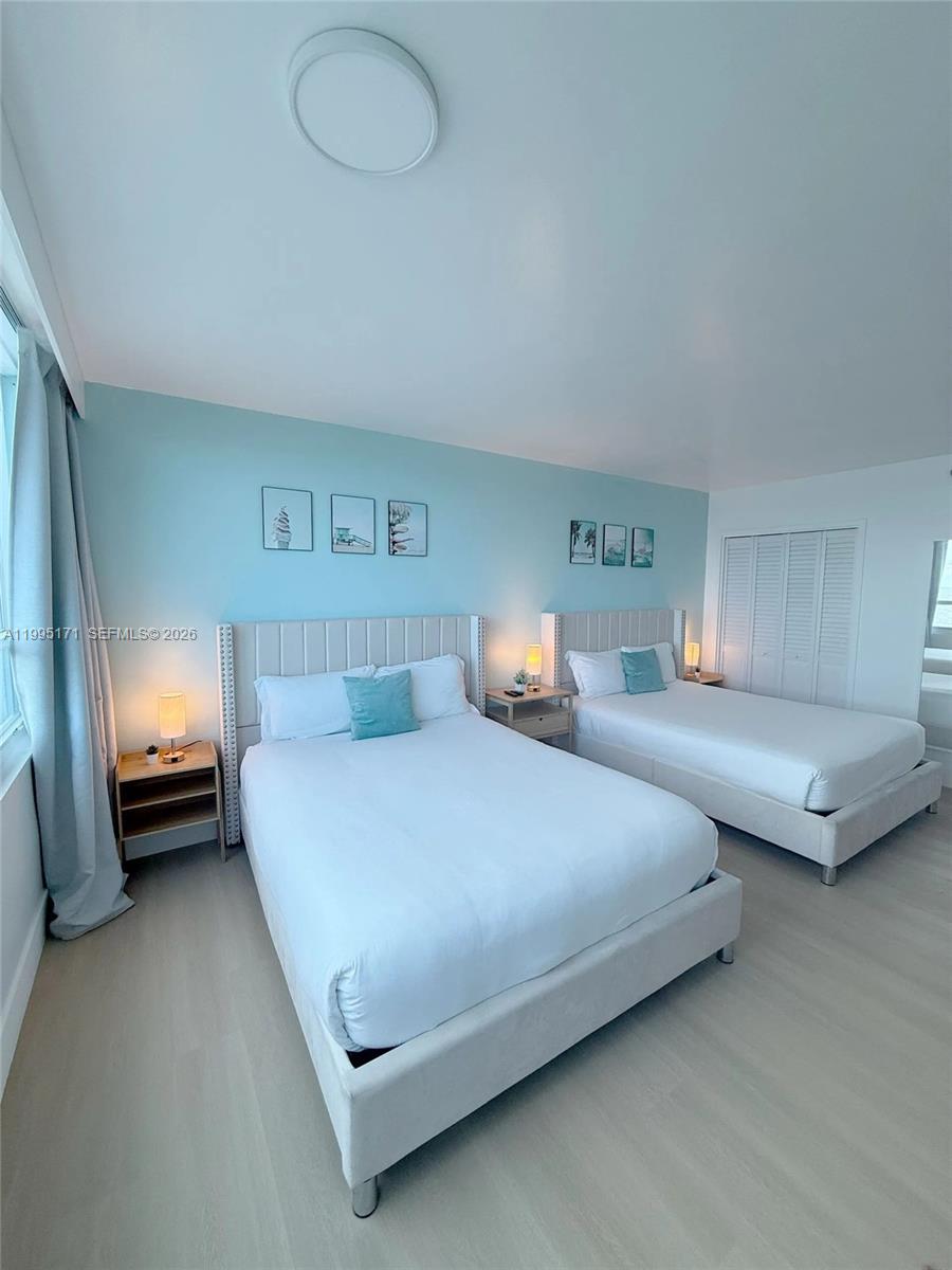 A bedroom features two beds with light-colored upholstered headboards against a light blue wall — 5445 Collins Ave # 635, Miami Beach FL 33140, MIAMI BEACH, FL